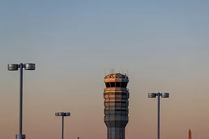 AN AIR TRAFFIC CONTROL TOWER IS SILHOUETTED AGAINST A SUNSET SKY