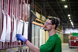 A WORKER WEARING AN AUDIO HEADSET FACES A PICKING STATION