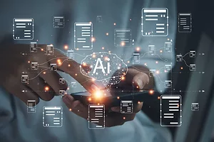 DIGITAL RENDERINGS OF CHARTS AND A BRAIN WITH THE LETTERS "AI" APPEAR ABOVE A CELL PHONE BEING HELD IN A PAIR OF HANDS.