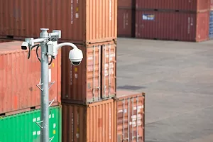 Shipping containers in a port with security cameras in the foreground.