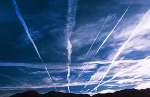MULTIPLE WHITE VAPOR TRAILS STREAK ACROSS A BLUE SKY