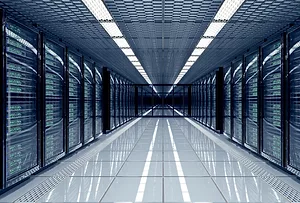 A long hallway with rows of dark-colored computer servers stacked on either side, split by a white linoleum floor