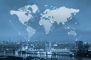 A visualization of a world map with lines connecting countries, interposed in the sky above a cityscape along the water, with the whole image tinted light blue