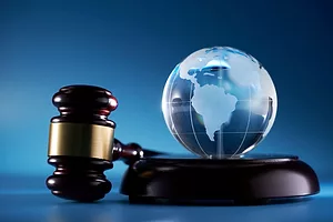A GAVEL AND SOUND BLOCK LIE NEXT TO A GLASS ORB ETCHED WITH A MAP OF THE EARTH