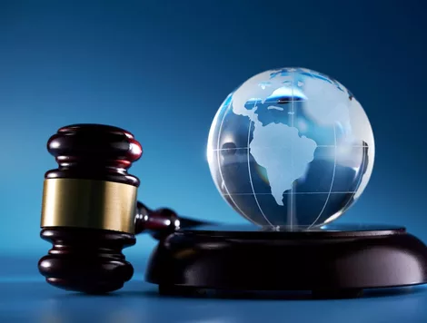 A GAVEL AND SOUND BLOCK LIE NEXT TO A GLASS ORB ETCHED WITH A MAP OF THE EARTH