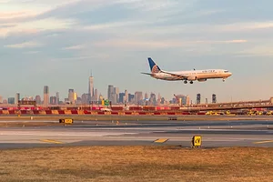 A United Airlines jet landing in front of the Manhattan Skyline