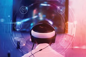 A PERSON WEARING A VIRTUAL REALITY HEADSET IS SEEN FROM BEHIND, WITH SWIRLING GRAPHIC IMAGES FORMING A CIRCLE AROUND THEIR HEAD.