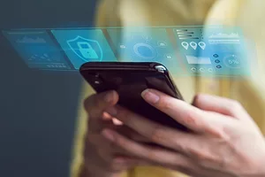 A pair of hands holding a smartphone, with a row of blue square icons projecting out of the phone