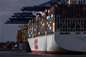A GIANT CONTAINER SHIP, LOADED WITH CONTAINER, SITS UNDER CRANES AT A DOCK