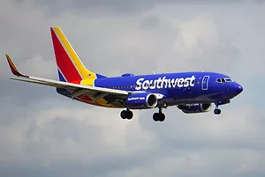 A PLANE BEARING THE RED GOLD AND BLUE COLORS OF SOUTHWEST AIRLINES FLIES THE SKIES
