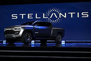 A GLEAMING NEW, SAPPHIRE COLORED PICKUP TRUCK SITS ON A POLISHED FLOOR, THE WORD STELLANTIS PICKED OUT IN LIGHTS BEHIND IT