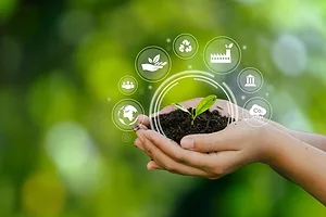 TWO HANDS HOLD UP A CLOD OF EARTH WITH A SMALL GREEN PLANT GROWING OUT OF IT, SURROUNDED BY SYMBOLS FOR FINANCE, TRANSPORTATION ETC.