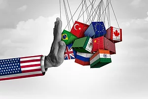 A COLORFUL CARTOON SHOWS A GIANT ARM CLAD IN THE AMERICAN FLAG PUSHING BACK A CLUSTER OF CONTAINERS BEARING THE FLAGS OF MULTIPLE NATIONS