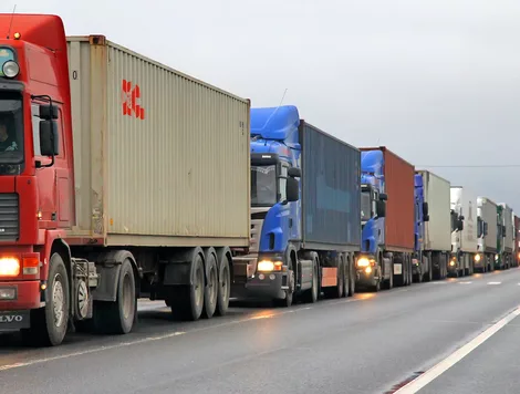 SEVERAL TRACTOR TRAILERS ARE LINED UP ONE AFTER ANOTHER ON A HIGHWAY.