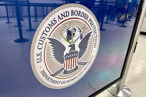 A SIGN AT AN AIRPORT CHECKIN LINE SHOWS THE INSIGNIA OF AN EAGLE AND US CUSTOMS AND BORDER PROTECTION DEPARTMENT OF HOMELAND SECURITY